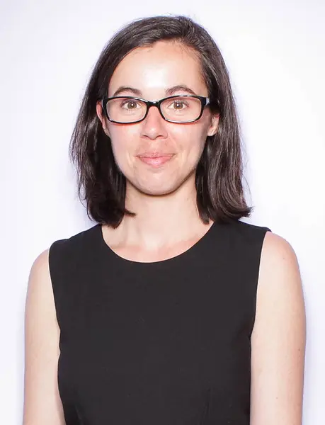 Photograph of Emily Capellari wearing a black dress and glasses.
