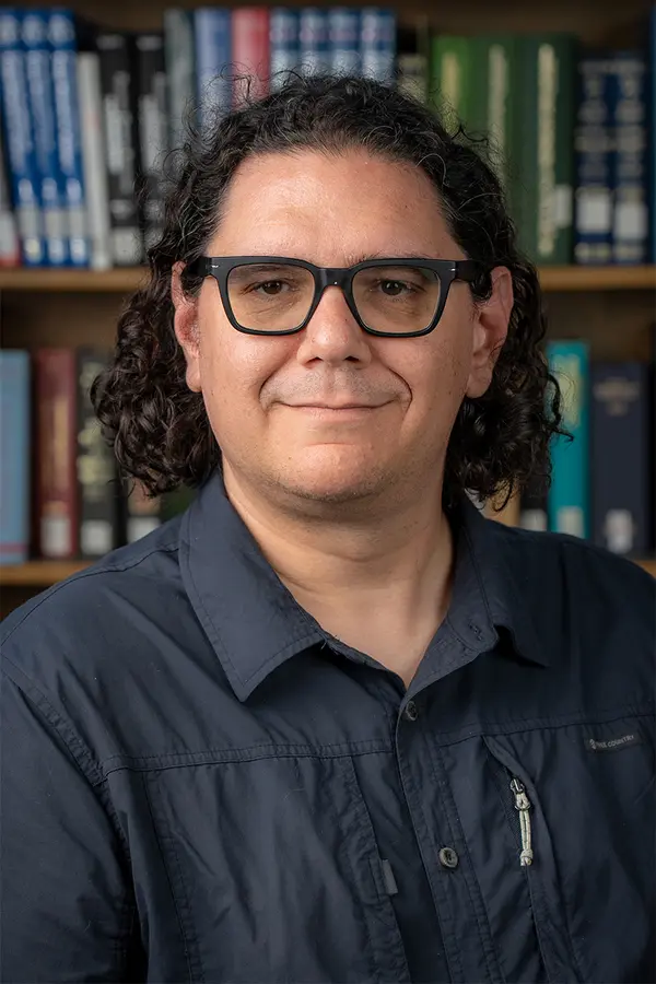 Photo of Justin Schell in front of a bookcase